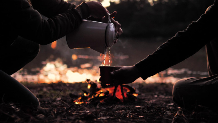 People pouring a warm drink around a campfire preview 1
